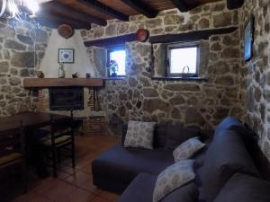 a living room with a blue couch and a stone wall at Casa Rural Generoso in Madroñal