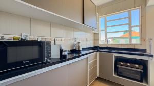 a large kitchen with a microwave and a window at Europa Place in Porto Alegre