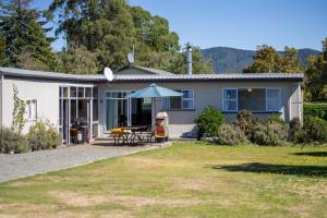 a house with a table and an umbrella at Mountain Serenity - Te Anau Holiday Home in Te Anau