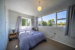a bedroom with a bed and two windows at Mountain Serenity - Te Anau Holiday Home in Te Anau