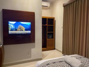a bedroom with a flat screen tv on a wall at Griya Alit Guest House in Ketewel