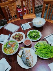 Una mesa de madera con platos de comida encima. en KND Wind Valley Bình Thuận, en Xóm Chum Găng