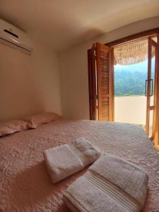 a bedroom with a bed with two towels on it at Suíte 3 Vila dos Pescadores Condomínio Portogalo in Angra dos Reis