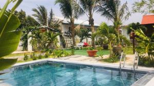 a swimming pool in a yard with palm trees at My Anh Garden in Ấp Thiẹn Ái