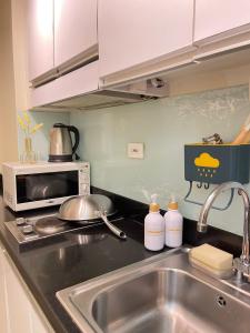 a kitchen counter with a sink and a microwave at Orchids Shore Residences Direct Pool Access in Manila