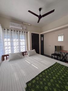 a bedroom with a large bed with a ceiling fan at Hornbill inn in Cochin
