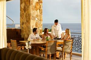 a group of people sitting around a table in a restaurant at Grand Solmar Land's End Resort & Spa in Cabo San Lucas