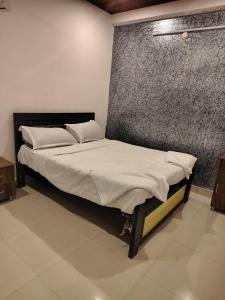 a bed with white sheets and pillows in a room at KOTLAS Highliving Service Apartments in Gachibowli