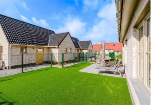 a yard with a fence and green grass at Tzeehuisje 57P in Oostduinkerke