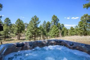 einen Whirlpool auf einem Feld mit Bäumen im Hintergrund in der Unterkunft Spacious Cozy Cabin Retreat on 5-Acres with HotTub in Elden Pueblo
