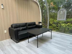 a black couch sitting in a room with a table at 2-bedroom Capsule House #30 in Parry Sound