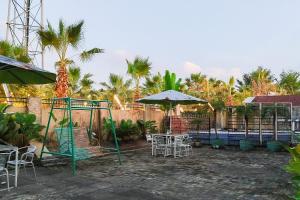 een terras met tafels, stoelen en parasols bij RedDoorz near Focal Point Medan in Sunggal