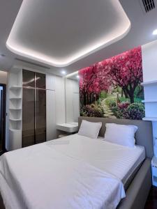 a bedroom with a white bed with a painting on the wall at Diamond Crown Hải Phòng in Ðông Khê