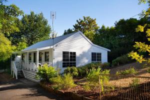a white house with a garden in front of it at Springview Cottage- captivating bush retreat in Hepburn Springs +9 photos