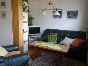 ein Wohnzimmer mit einem schwarzen Ledersofa und einem Couchtisch in der Unterkunft Ferienwohnung Panorama in Rauenstein