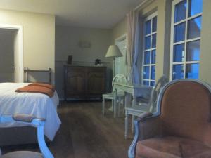 a bedroom with a bed and a chair and windows at Ros & Marc Boutique Accommodation in Wezembeek-Oppem