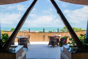 a patio with chairs and tables and the ocean in the background at Divi-Divi Praia Hotel in Natal