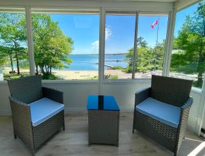 two chairs and a table in a room with a view of the ocean at Georgian Bay 3-bdrm lakefront Main House in Dillon