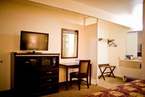 a hotel room with a television and a desk with a chair at Whispering Palms Inn in Del Rio