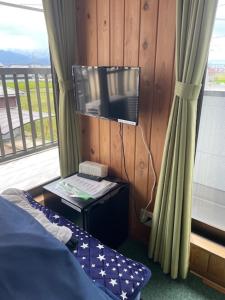a bedroom with a bed and a tv and a window at 合同会社ゲストハウス縁 in Saijo