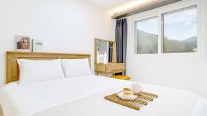 a bedroom with a white bed and a window at Gapyeong Orion PoolVilla pension in Gapyeong
