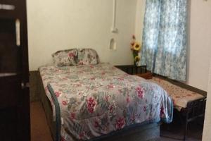 Un dormitorio con una cama con colcha floral y una ventana. en OUR FARM Agro-Eco Tourism and Farm Stay, en Helwāk