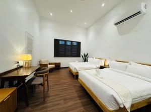 Un dormitorio con dos camas y un escritorio y una mesa. en 1917 By MUO, en Muar