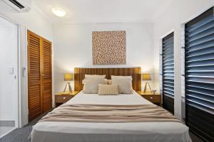 a bedroom with a large bed with two tables and two lamps at Beach-Apartments Close to Town in Port Douglas