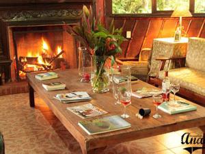 a wooden table with wine glasses and a fireplace at El Septimo Paraiso in Mindo