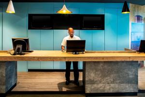 a man standing at a counter with a laptop at ibis Macae in Macaé