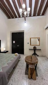 a bedroom with a bed and a table and a chandelier at Hotel Edzna in Campeche