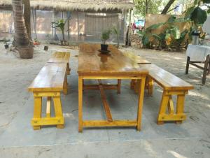 a wooden table and benches with a potted plant on it at Yoga Culture Palolem in Palolem