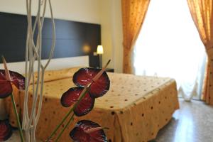 a bedroom with a bed and a vase with flowers at Hotel Gabbiano in Mola di Bari