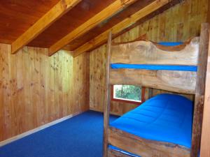 a room with two bunk beds in a log cabin at Cabañas Rukalafquen in Licán Ray