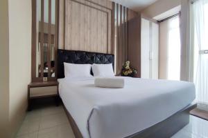 Una cama blanca grande en una habitación con ventana. en Comfortable and Modern 1BR without Living Room at Amartha View Apartment By Travelio, en Semarang