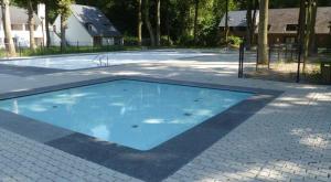 a large blue swimming pool on a brick ground at Domein Hengelhoef in Aan de Wolfsberg