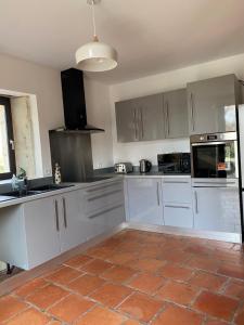 a kitchen with white cabinets and a tile floor at Le gîte de Mauvielle in Solomiac