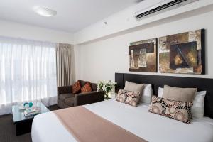 a bedroom with a large white bed and a couch at Oaks Ipswich Aspire Suites in Ipswich