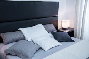 1 cama con almohadas blancas y cabecero negro en Casa Alberone, en Roma