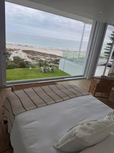 a bedroom with a bed and a large window at Sunset Shores in Lambertʼs Bay