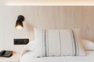 a bed with a white pillow and a black lamp at Minura Cala Galdana & Apartamentos d'Aljandar in Cala Galdana