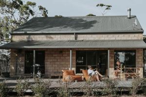 two women sitting on chairs in front of a building at Waterfront - Hot Tub - Sauna - Serenity in Coles Bay