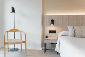 a bedroom with a bed and a chair next to a table at Minura Cala Galdana & Apartamentos d'Aljandar in Cala Galdana +27 photos