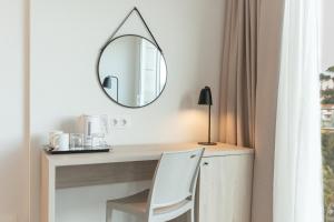 a mirror on a desk with a white chair at Minura Cala Galdana & Apartamentos d'Aljandar in Cala Galdana
