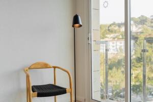 a chair in a room with a window and a lamp at Minura Cala Galdana & Apartamentos d'Aljandar in Cala Galdana
