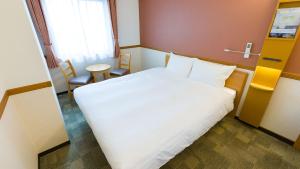 a hotel room with a large white bed and chairs at Toyoko Inn Yonago Ekimae in Yonago
