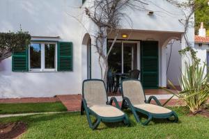 two chairs sitting in the grass in front of a house at Minura Cala Galdana & Apartamentos d'Aljandar in Cala Galdana