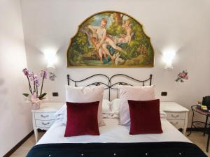 a bedroom with a painting above a bed with red pillows at Villamena in Spello