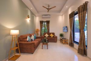 a living room with two couches and a ceiling fan at Canary Villa by Tropicana Stays in Lonavala