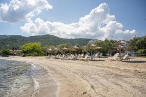 a group of chairs and umbrellas on a beach at Aegean Sun Hotel in Skala Rachoniou